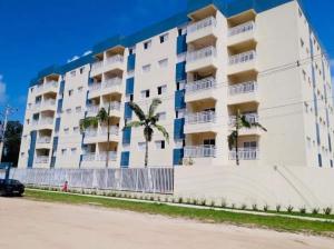 a white building with palm trees in front of it at APTO FAMILIAR EM BERTIOGA JARDINS DO INDAIÁ A 500 M Praia in Bertioga