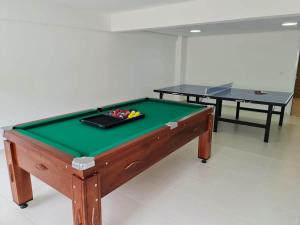 a ping pong table in a room with two tables at APTO FAMILIAR EM BERTIOGA JARDINS DO INDAIÁ A 500 M Praia in Bertioga