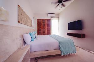 1 dormitorio con 1 cama blanca y TV de pantalla plana en Casa Astral Luxury Hotel, en Isla Holbox