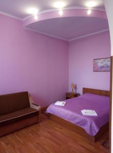 een paarse slaapkamer met een bed en een bank bij Готель "У Свата" Гришківці Бердичівський р-н in Hryshkivtsi