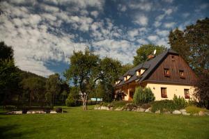 una casa con techo de gambrel en un césped verde en Penzion pod Stráni en Malá Morávka