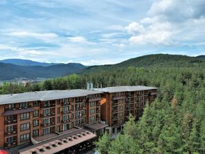 a building in the middle of a forest with mountains at Maxi Park Hotel & Spa in Velingrad