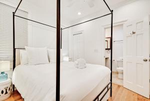 Guesthouse Charleston SOUTH 105 A and B في تشارلستون: غرفة نوم بيضاء مع سرير كبير وحمام