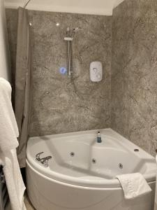 a bathroom with a bath tub and a shower at Pinewood Cottage Self Catering Apartments and studio apartments in Lyndhurst