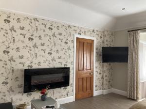 sala de estar con chimenea y papel pintado con motivos florales en Pinewood Cottage Deluxe Self Catering Apartments, en Lyndhurst