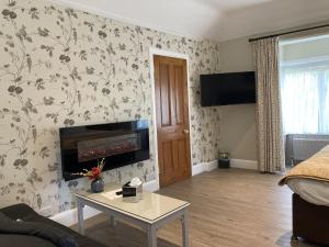 sala de estar con chimenea y papel pintado con motivos florales en Pinewood Cottage Deluxe Self Catering Apartments, en Lyndhurst