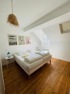 ein weißes Schlafzimmer mit einem Bett und Holzboden in der Unterkunft Appartement avec balcon au coeur de la Baule in La Baule