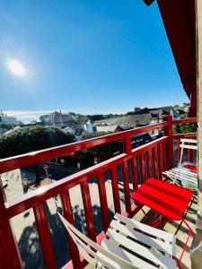 ein roter Balkon mit weißen Stühlen und einem roten Geländer in der Unterkunft Appartement avec balcon au coeur de la Baule in La Baule