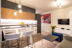 a kitchen with white and black cabinets and a bar with stools at Aparthotel NOX in Cluj-Napoca