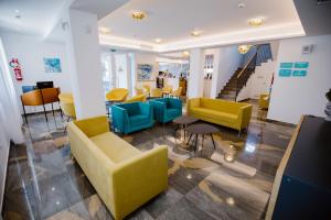 a lobby with yellow and blue chairs and stairs at Principe Alogna Hotel & SPA in Altavilla Milicia