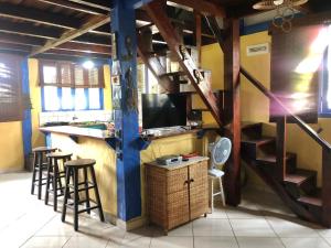 a bar with stools and a television in a room at Chalés no centro de Bombinhas in Bombinhas
