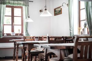 a dining room with tables and chairs and windows at Penzion U Churáňů in Stachy