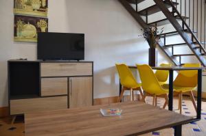 a living room with a tv and a table and yellow chairs at Apartamentos Turísticos - Hostal Los Alisos in Aliseda