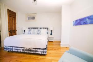 a white bedroom with a bed and a wooden floor at Guesthouse Charleston SOUTH 82 A and B in Charleston