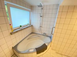 a bath tub in a tiled bathroom with a window at Appartement Apelern (A2) - 2 Zimmer, Badewanne, Terrasse, Netflix in Apelern