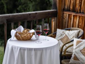 Dois copos de vinho numa mesa com um cesto. em Bnb Lettnerhof Balcony Family Suite em Monguelfo
