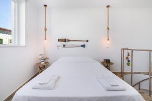 a white bed in a room with a window at Casa Cachalote in Ferragudo