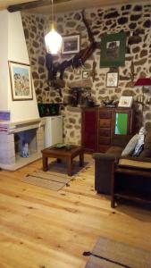 a living room with a stone wall with a couch and a table at Casa da Ti Maria Pereira in Monsanto