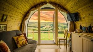 uma sala de estar com uma grande janela arqueada com vista em Forester's Retreat Glamping - Cambrian Mountains View em Aberystwyth