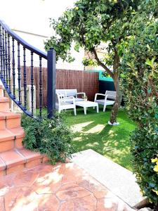 un patio con 2 bancos blancos y un árbol en Apartamento Casa Tambo, Campelo, en Pontevedra