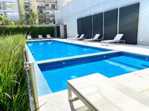 a swimming pool with lounge chairs next to a building at Palermo Soho Trendy Studio II in Buenos Aires