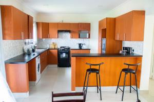 una cocina con armarios de madera y 2 taburetes de bar en Modern & secure apartment in Area 43 Lilongwe - self catering en Lilongüe