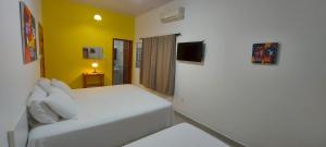 a bedroom with a white bed and a yellow wall at Recanto na Floresta in Rio Branco