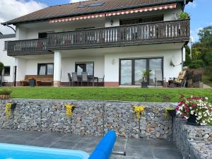 a house with a stone wall and a blue pool at Haus Sonnenschein in Holzbach