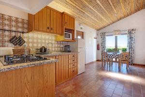 a kitchen with wooden cabinets and a table with chairs at Monte do Tanoeiro - Casa Adega in Rogil