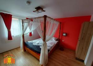 1 dormitorio con cama con dosel y paredes rojas en POARTA SOARELUI en Teliucu Inferior