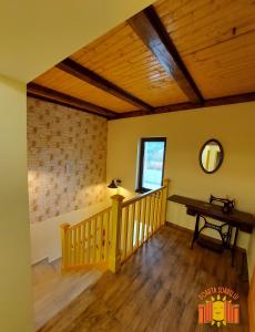 Habitación con escalera de madera, mesa y espejo. en POARTA SOARELUI, en Teliucu Inferior
