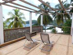 Duas cadeiras numa varanda com vista para o oceano em Villa Fleurs Amande em Marigot