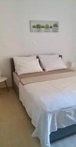 łóżko z białą pościelą i poduszkami w pokoju w obiekcie Marina Apartment w mieście Artemida