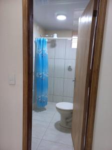 a bathroom with a toilet and a blue shower curtain at Ciudad del Este - Departamento con 2 habitaciones, Paraguay in Ciudad del Este