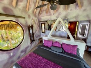 a bedroom with a bed with purple pillows and a window at Sueños Tulum in Tulum