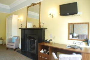 een kamer met een open haard, een bureau en een spiegel bij The Salisbury Hotel in Edinburgh