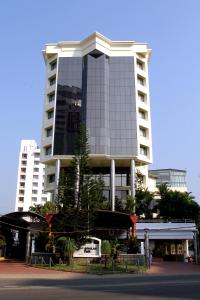 ein hohes Gebäude mit vielen Bäumen davor in der Unterkunft Gokulam Park in Kochi