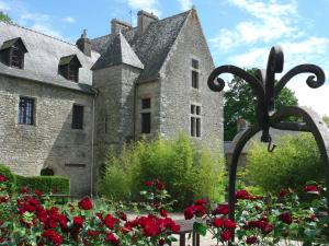 un viejo castillo con flores rojas delante de él en La Maison OBONO en Le Bono
