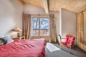 a bedroom with a red bed and a chair and a window at L'Écrin Alpin - Welkeys in Megève