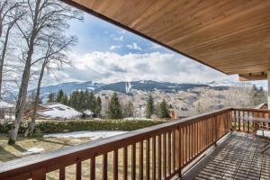 a wooden balcony with a view of the mountains at L'Écrin Alpin - Welkeys in Megève