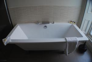 a white bath tub sitting next to a white sink at The Salisbury Hotel in Edinburgh