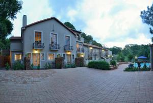 une grande maison blanche avec une allée en briques dans l'établissement Duke & Duchess Boutique Hotel, à Pretoria