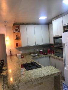 eine Küche mit weißen Schränken und einer Granitarbeitsplatte in der Unterkunft Casa Aconchego dos Canyons in Praia Grande