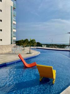 a pool with a yellow and red slide in the water at Apartamento aconchegante vista mar e piscina em cond de Arraial do Cabo in Arraial do Cabo