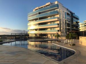 ein Gebäude mit einem Pool vor einem Gebäude in der Unterkunft Apartamento aconchegante vista mar e piscina em cond de Arraial do Cabo in Arraial do Cabo