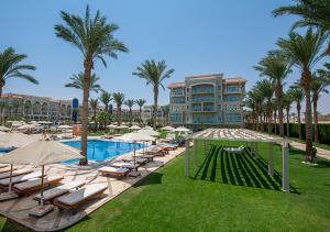 a resort with a pool and lounge chairs and palm trees at Premier Le Reve Hotel & Spa Sahl Hasheesh - Adults Only 16 Years Plus in Hurghada