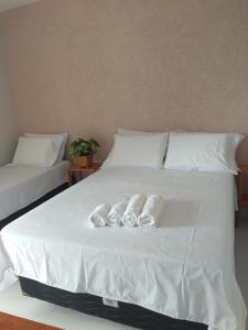 uma cama branca com quatro almofadas em Divina Pousada na Ilha de Boipeba