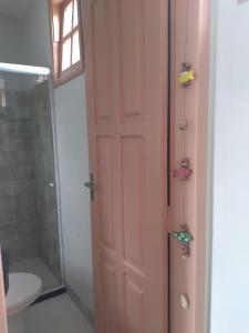 uma casa de banho com um chuveiro, um WC e uma porta em Divina Pousada na Ilha de Boipeba