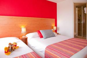 two beds in a hotel room with red walls at The Originals City, Hôtel Mâcon Sud in Chaintré