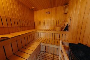 an inside of a wooden sauna with benches and a bucket at Pensiunea Mirabilandia in Negreni